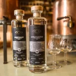 Babylon Berlin Libertinage Vodka und Ambassadeur Gin Flaschen mit Tasting-Gläsern vor der Kupferbrennerei
