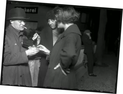Historisches Foto: Mann mit Hut und Zigarette im Gespräch mit zwei Frauen auf einer Berliner Straße bei Nacht